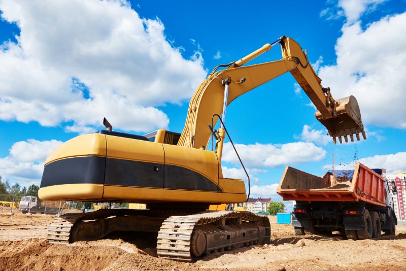 excavator machine scooping earth into a dump truck